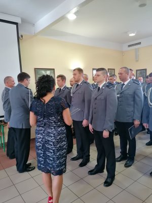 Na zdjęciu widać policjantów, którzy awansują na wyższe stopnie służbowe. Zastępca Komendanta Wojewódzkiego Policji w Poznaniu wręcza policjantom akty mianowania