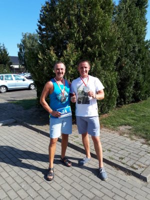 Na obrazie widać dwóch uczestników biegu w Wyszynie - insp. Romana Pisarskiego - Komendanta Powiatowego Policji w Pleszewie oraz kom. Bartosza Nowickiego. Stoją z medalami w rękach.