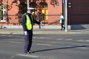 światło zielone - ruch otwarty dla nadjeżdżających z prawej i lewej strony policjanta; policjant wskazuje miejsce do zatrzymania się dla pojazdów nadjeżdżających z jego lewej strony z zamiarem skrętu w lewo