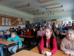 Na zdjęciu widać uczniów szkoły w Lenartowicach. Dzieci i młodzież siedzą w ławkach w szkolnej sali. Zdjęcie zostało zrobione podczas prelekcji na temat dopalaczy i narkotyków.