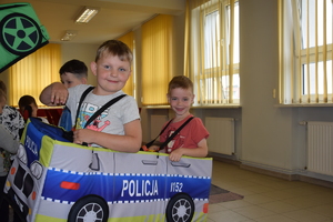 Na obrazie widać chłopca, który jest w autochodziku z napisem POLICJA