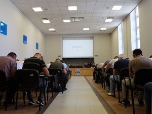 Policjanci bez munduru siedzą tyłem do zdjęcia na krzesłach