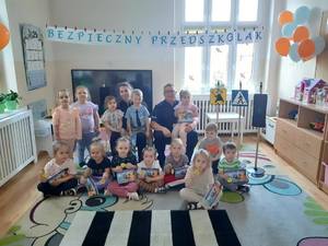 Na obrazie widać grupę dzieci, która pozuje do zdjęcia wspólnie z policjantami.
