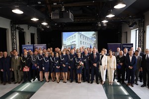 Na zdjęciu widać policjantów i pracowników cywilnych, którzy stoją do zdjęcia grupowego. W tle budynek KPP Pleszew.