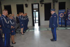 Na obrazie widać policjanta, który stoi bokiem do zdjęcia.