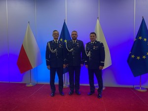 Na obrazie widać trzech policjantów, podczas wręczenia promes przed Komendanta Wojewódzkiego Policji w Poznaniu.