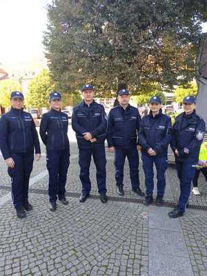 Na obrazie widać policjantów, którzy stoją obok siebie na płycie rynku obok UMiG Pleszew. Spotkanie odbyło się w ramach akcji Razem dla życia. Akcja polega na ćwiczeniu resuscytacji.