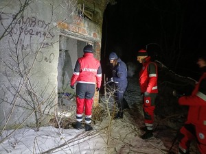 Na zdjęciu są ratownicy WOPPR i policjantka, którzy świecą latarkami w kierunku miejsca, gdzie mogą przebywać bezdomni