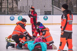 Na obrazie widać ratowników medycznych, którzy na sztucznym lodowisku robią pokaz pierwszej pomocy medycznej