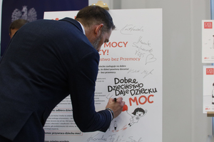 Na zdjęciu jest mężczyzna, który pisze na tablicy. Zdjęcie dotyczy kampanii Dzieciństwo bez przemocy